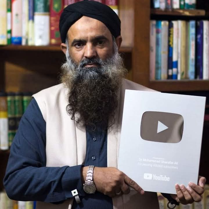 "Hakeem Sharafat Ali holding YouTube Silver Play Button Award for reaching 100,000 subscribers, standing in front of a bookshelf."
